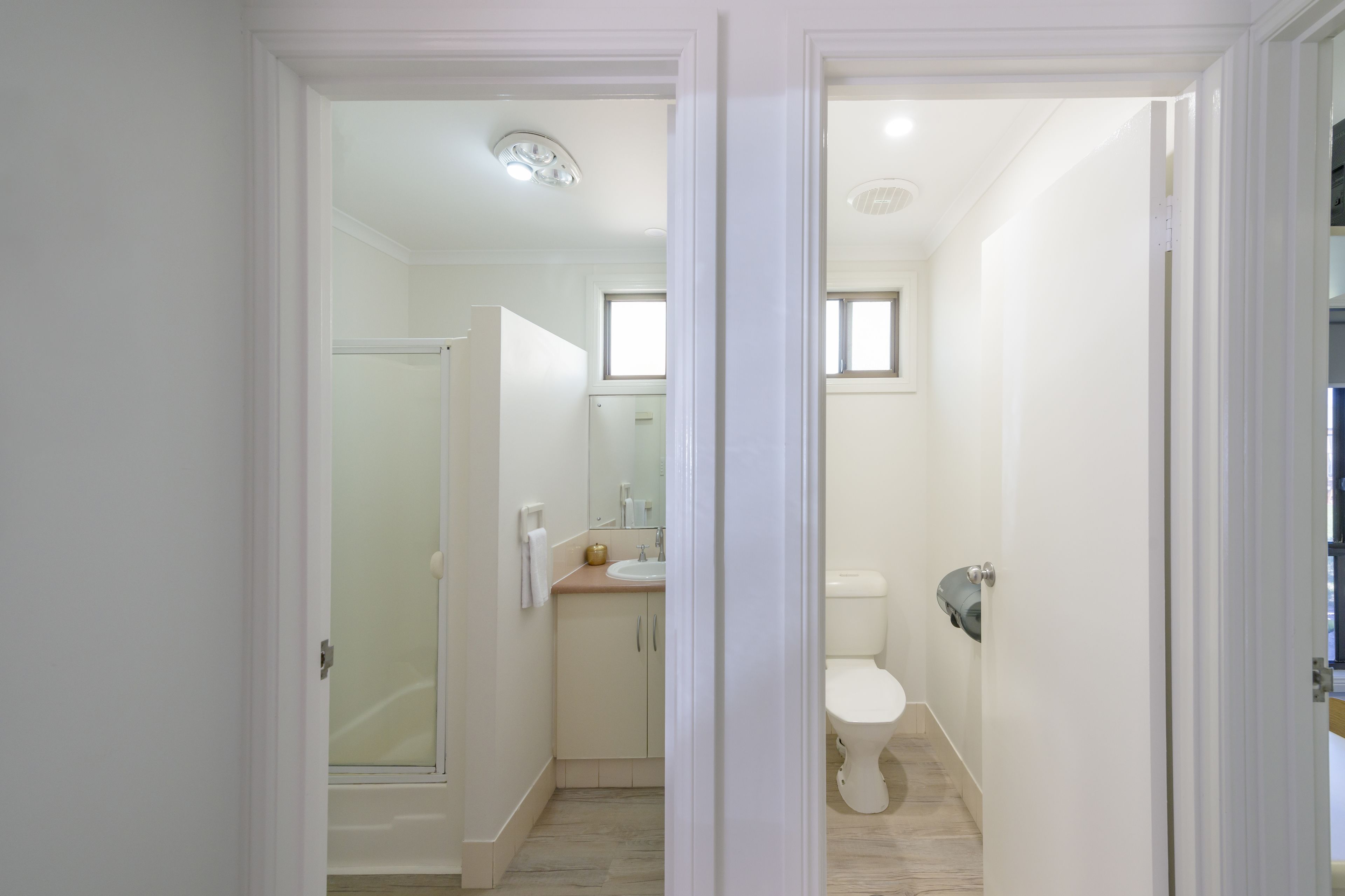 A modern bathroom with a glass shower enclosure, a sink with a mirror, and a toilet.