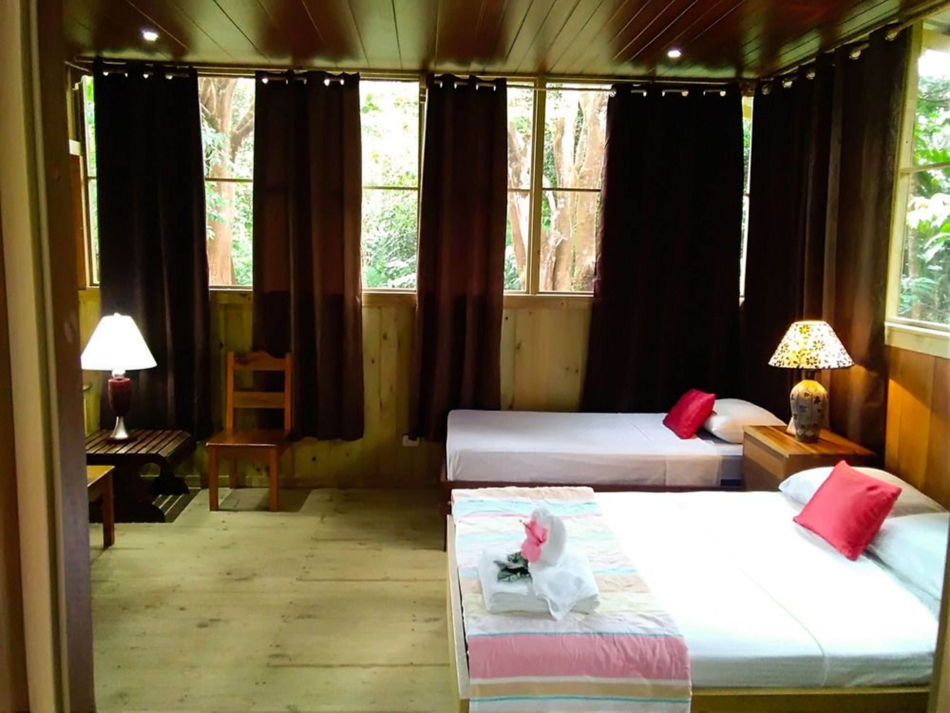 A room with two beds, a chair, a table, and a lamp.