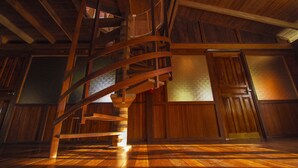 Un escalier en colimaçon dans un intérieur en bois, avec de hauts plafonds et un plancher poli.
