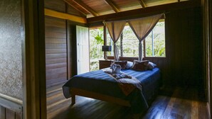 Une chambre dans une cabane en bois, avec un lit, des rideaux et une fenêtre.