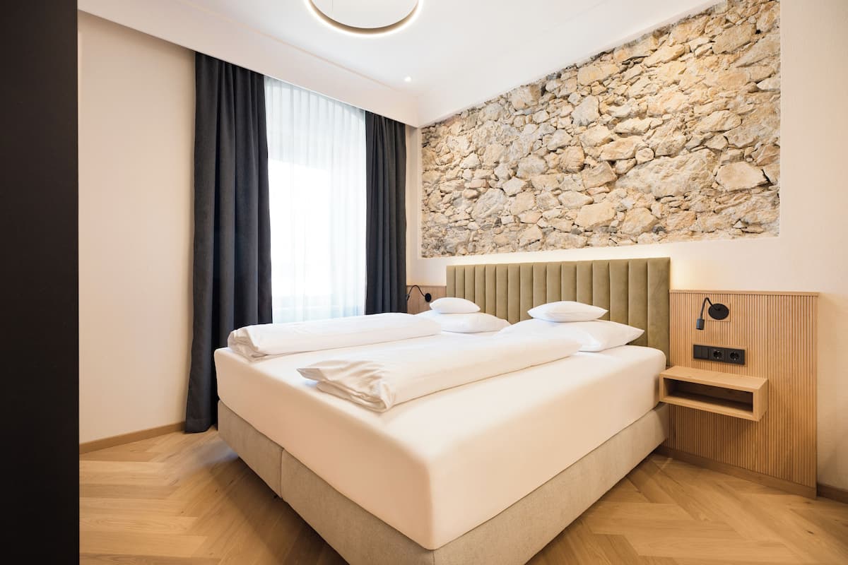 Ein modernes Schlafzimmer mit einem großen Bett, einer Steinwand und einem hölzernen Kopfteil.