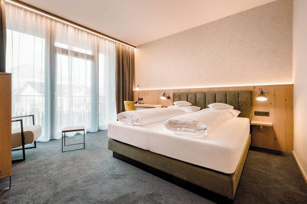 Ein Hotelzimmer mit einem großen Bett, einem Schreibtisch und einem Stuhl.