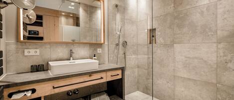 Un baño moderno con un espejo grande, un lavamanos y una ducha.