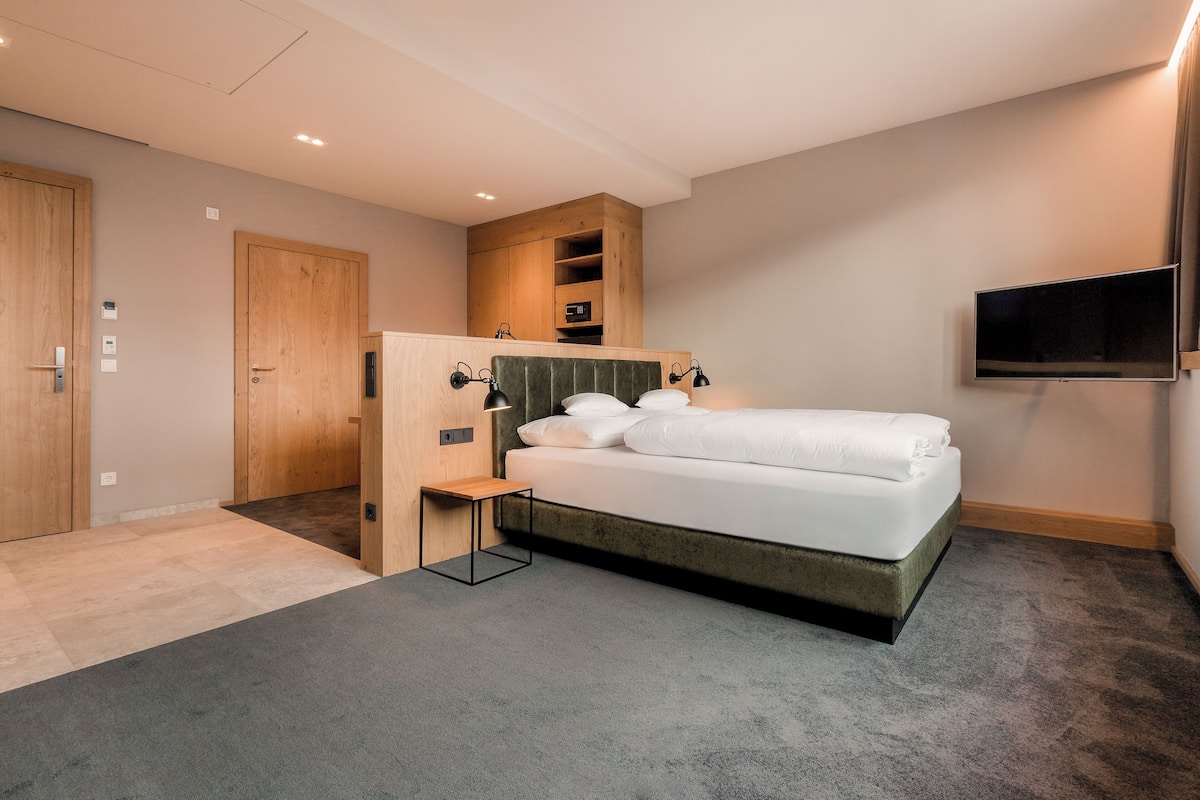 Ein modernes Schlafzimmer mit Bett, Nachttischen, Fernseher und integrierten Regalen.