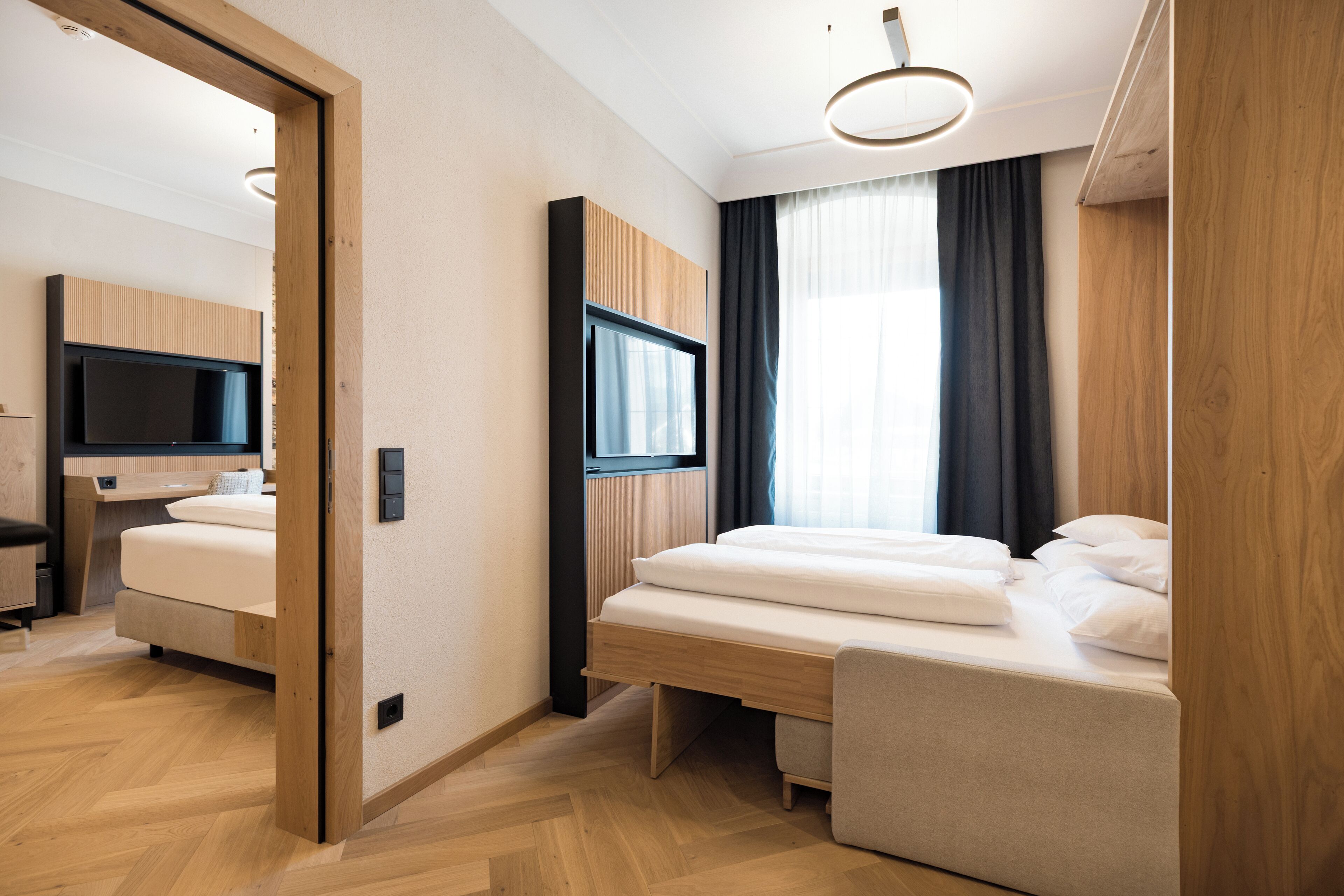Una habitación de hotel moderna con una cama de madera, un televisor y un escritorio con una silla.