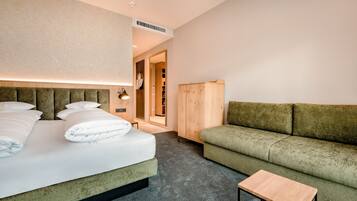 Una habitación de hotel moderna con una cama, un sofá verde, una pequeña mesa de madera y un armario.