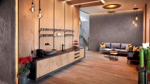A modern interior with a wooden reception desk, a grey sofa, and a staircase. - Gasthof Hotel Post (Strass im Zillertal)