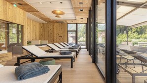 A spa room with wooden walls, large windows, and sunbeds. - Gasthof Hotel Post (Strass im Zillertal)
