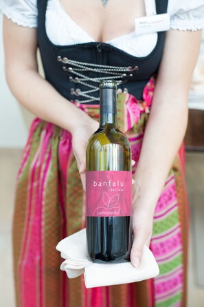 Una persona sosteniendo una botella de vino con una etiqueta que dice 'banfalu der rote'.