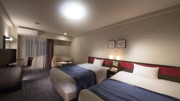 A hotel room with two beds, a desk with a TV, a chair, and a small table.