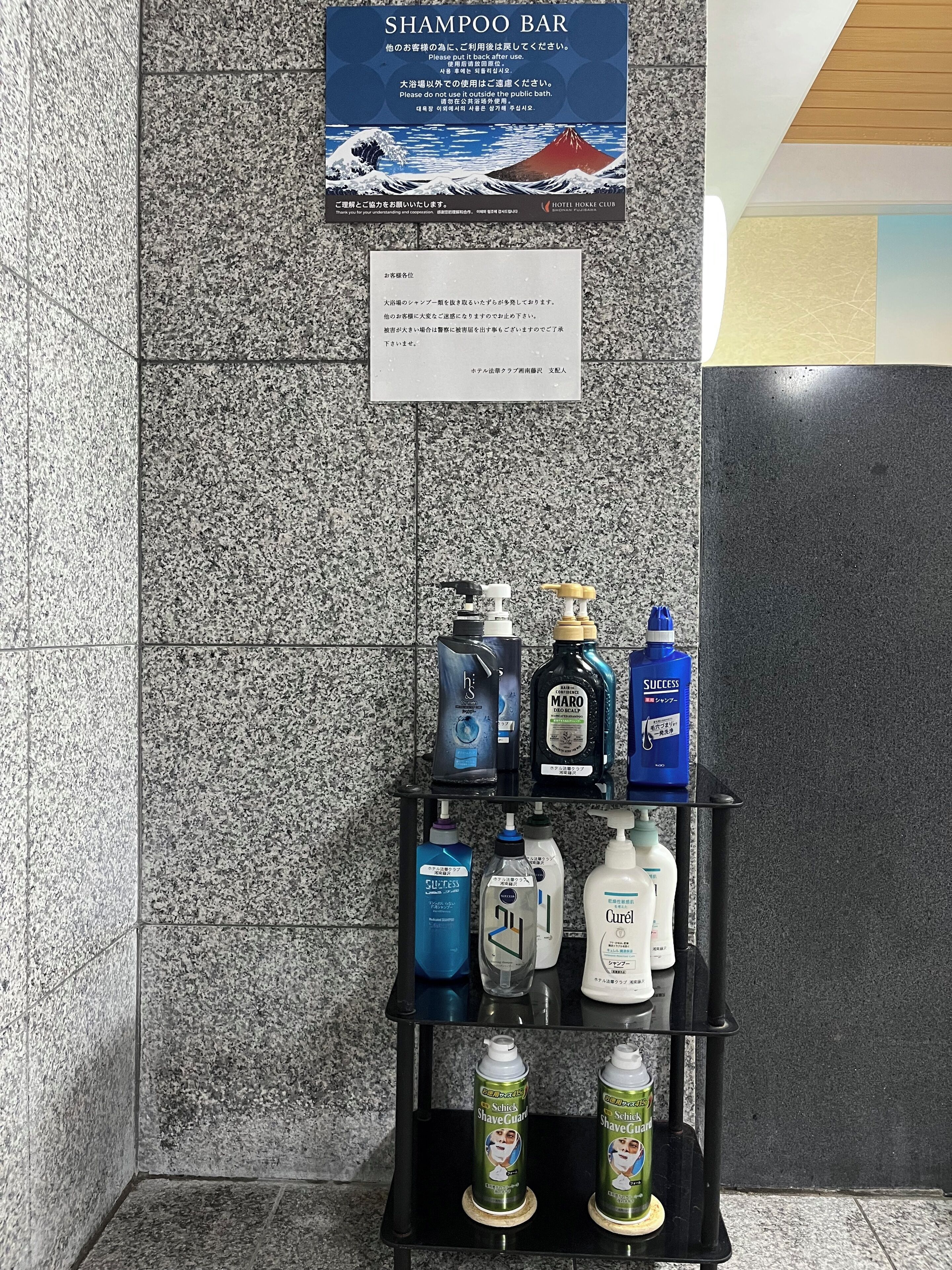 A shampoo bar with various hair care products on a shelf against a textured wall.