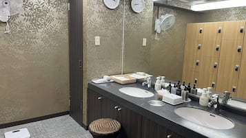 Un baño moderno con dos lavamanos, un espejo y un reloj en la pared.
