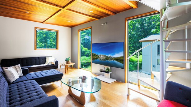 A modern living room with a sofa, glass coffee table, and a TV. - Wagaya (Hakuba)
