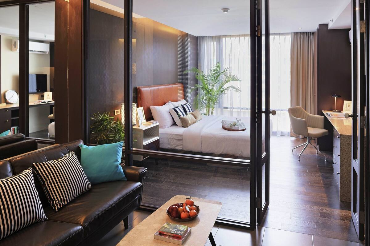 Ein modernes Hotelzimmer mit Bett, Sofa, Couchtisch und Schreibtisch.