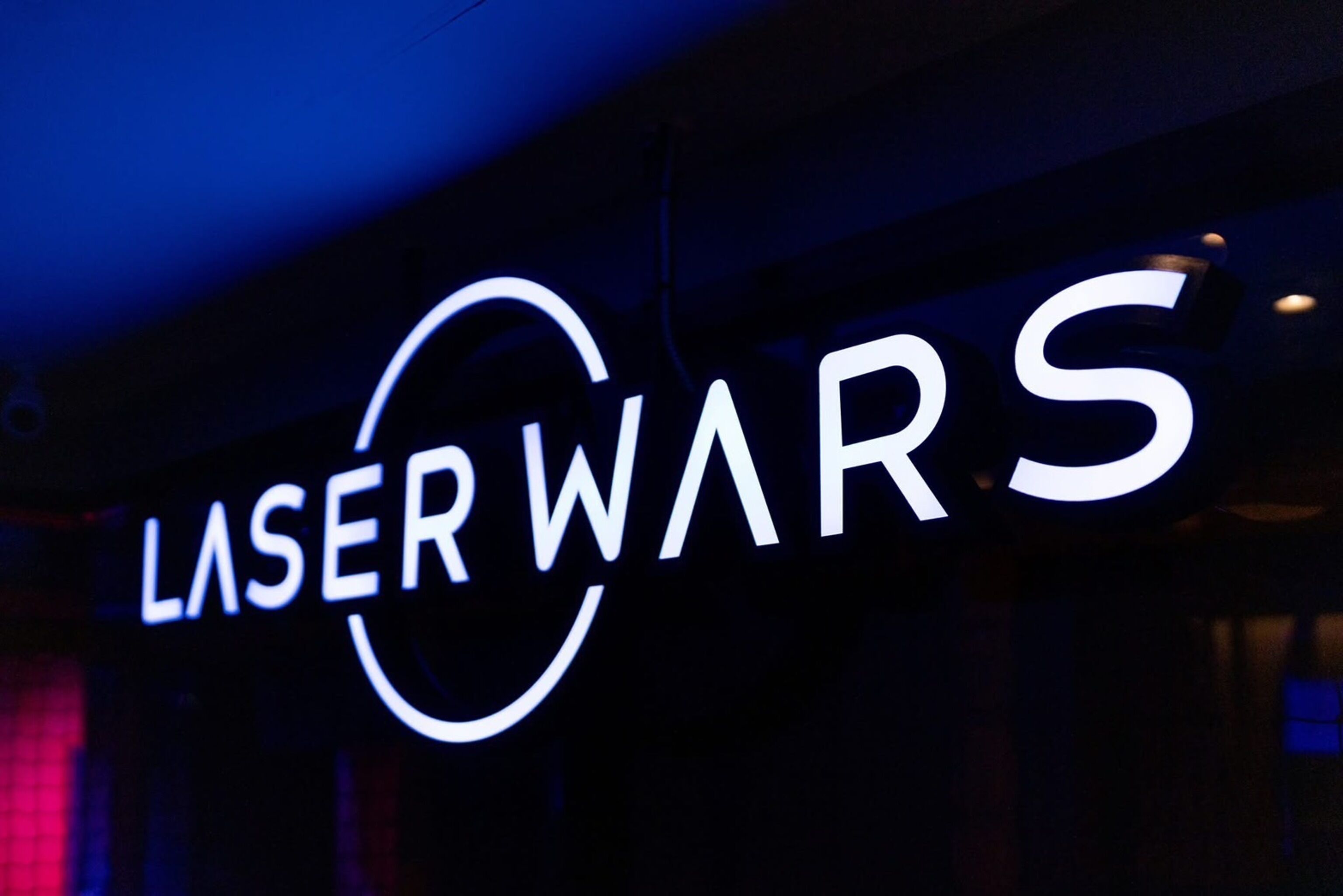 A sign with the text "LASER WARS" in white letters on a dark background.