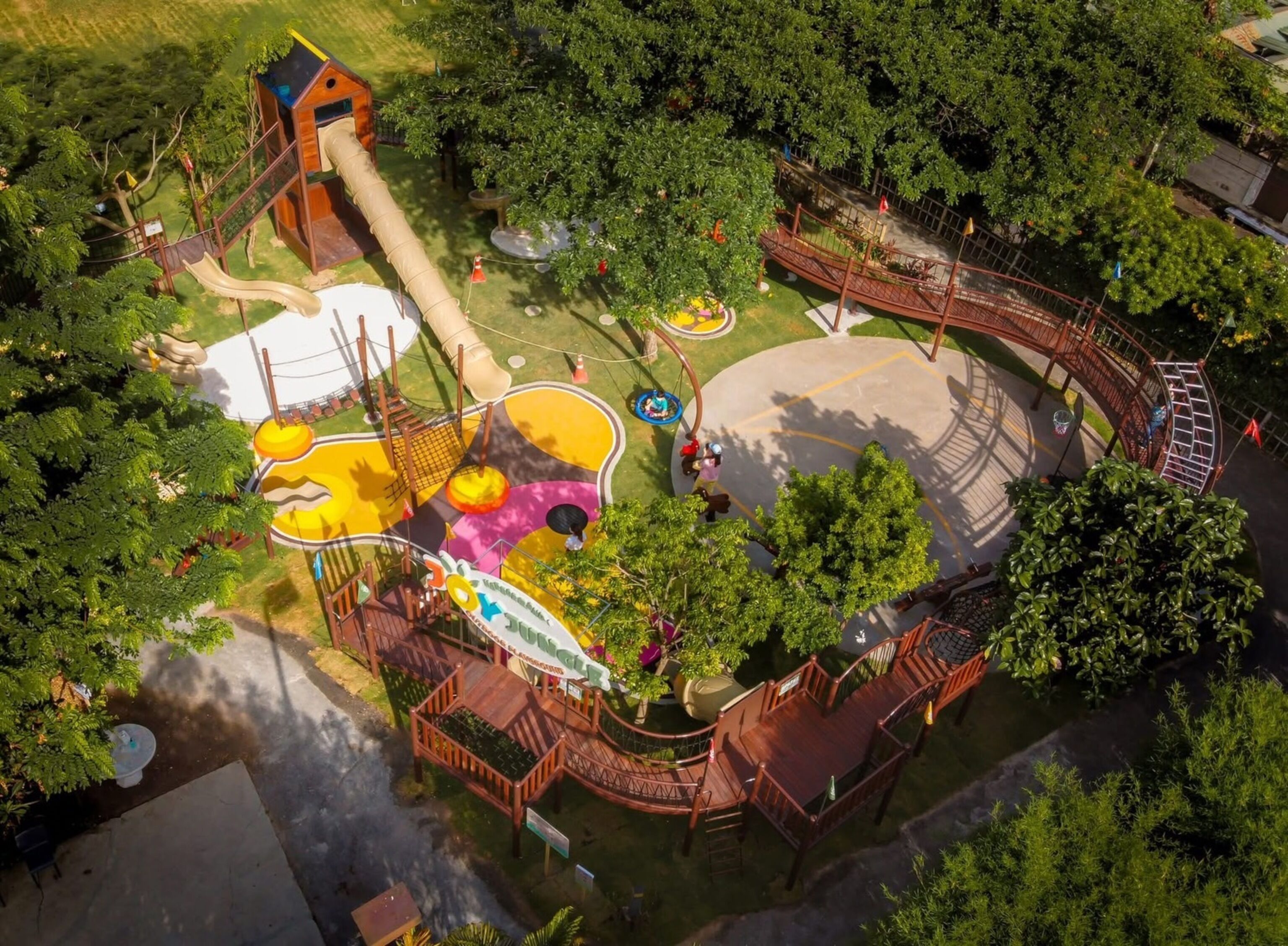 An aerial view of a playground with slides, swings, and a small wooden structure.