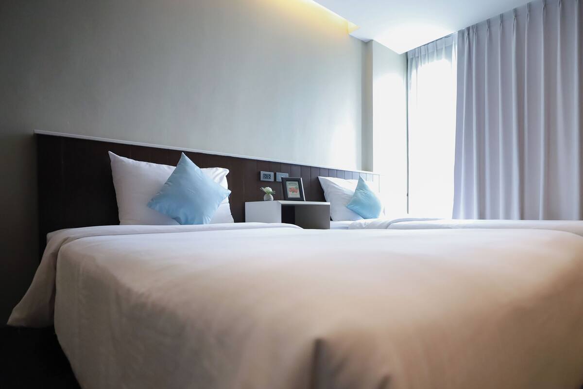 Ein Hotelzimmer mit einem großen Bett, einem Nachttisch und einem Fenster mit Vorhängen.