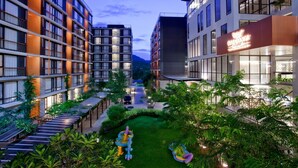 Ein modernes Hotel mit mehreren Etagen, Außenbereichen zum Verweilen und einem gepflegten Garten.
