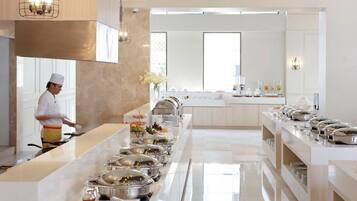 Una cocina moderna de hotel con barra libre, un chef preparando alimentos y un ambiente limpio y bien iluminado.