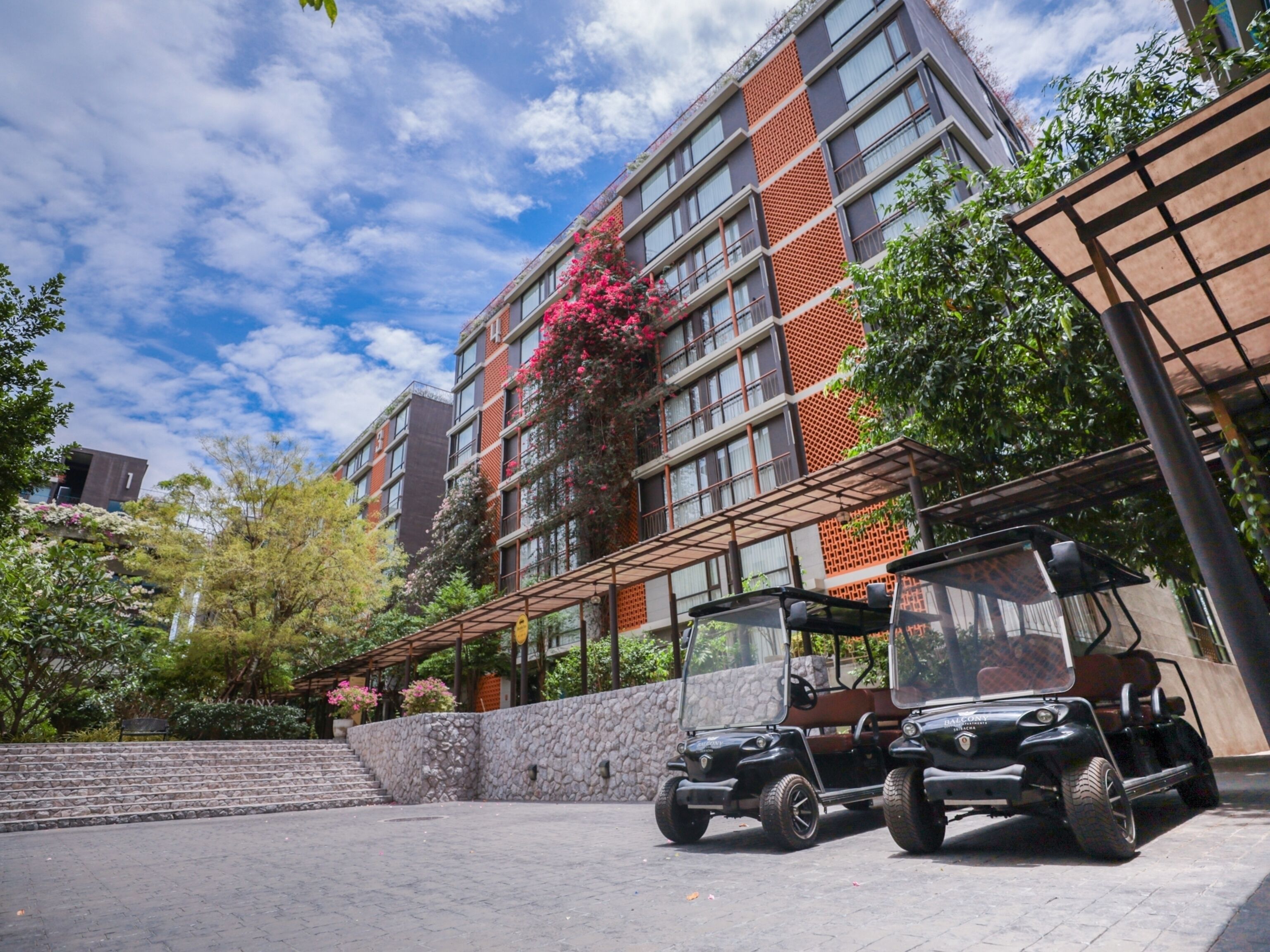 A multi-story building with a modern design, featuring a mix of brick and glass facades. There are two golf carts parked in front of the building.
