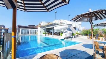 Una piscina al aire libre, sillones reclinables de piscina