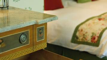A wooden dresser with drawers, a bed with a floral bedspread, and a green wall with a plant.