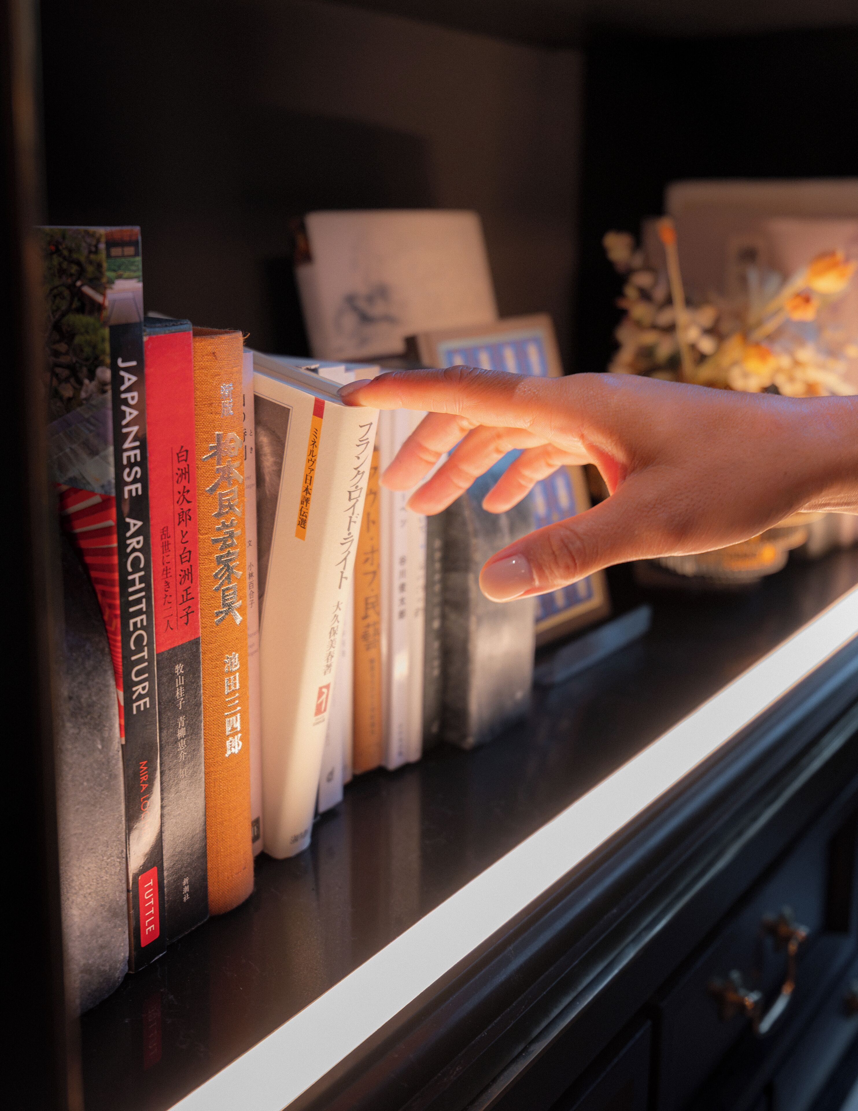 A hand reaching for a book on a shelf.