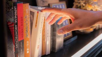 A hand reaching for a book on a shelf.