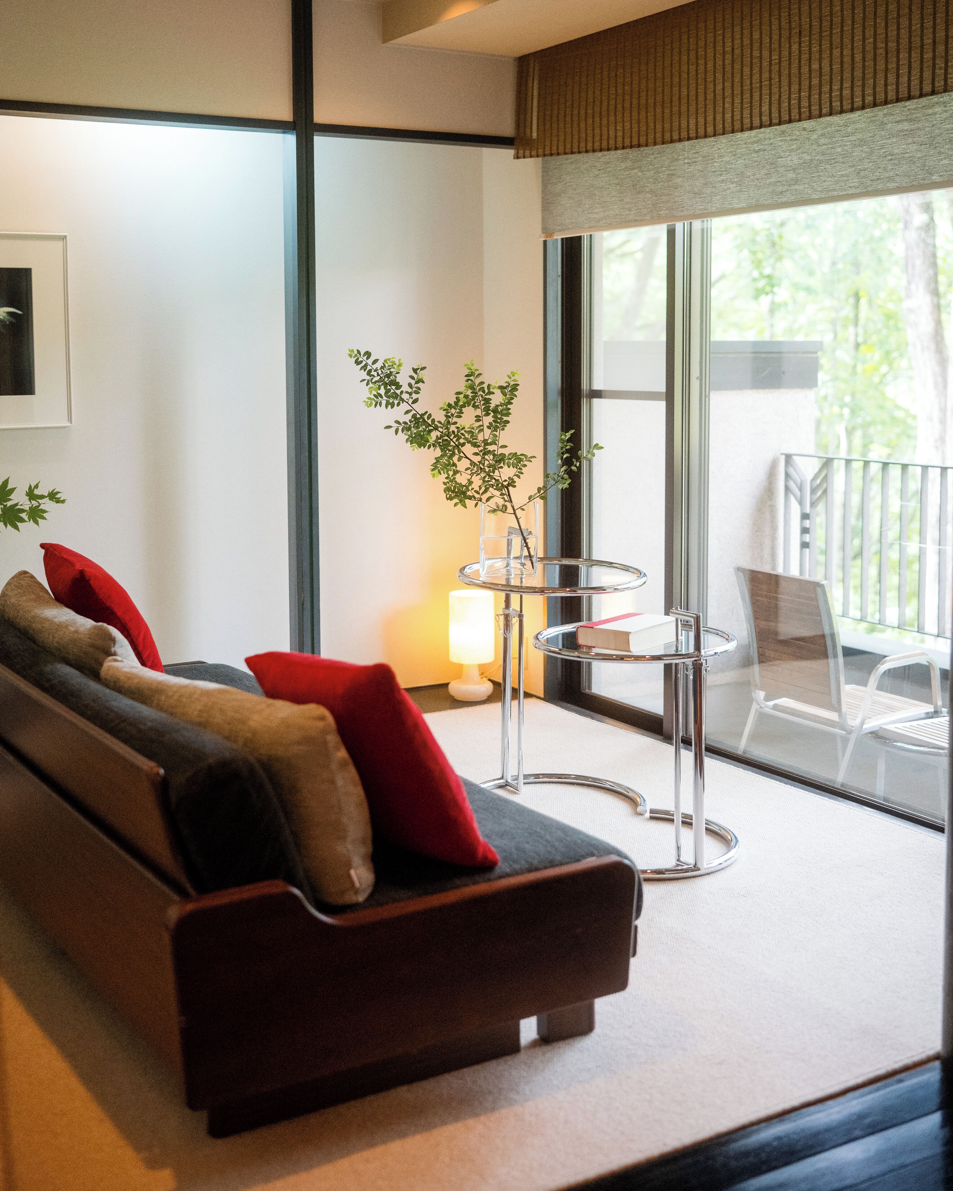 A modern living room with a sofa, a glass table, and a view of the outdoors.