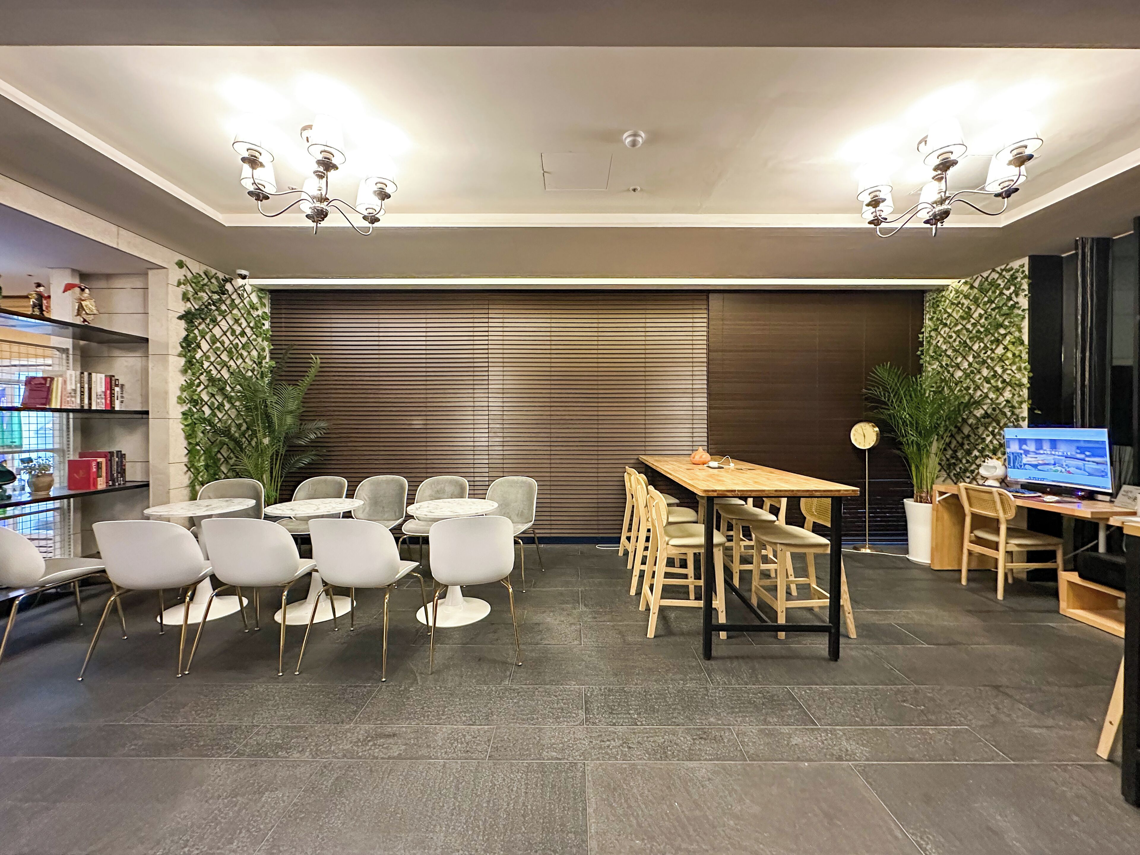 Un espace intérieur moderne comprenant un coin repas avec une table et des chaises en bois, une bibliothèque et des plantes décoratives.