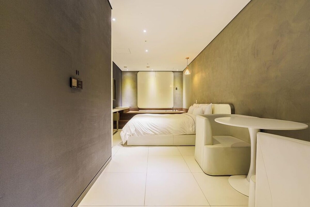 A modern bedroom with a bed, bedside tables, and a small round table.