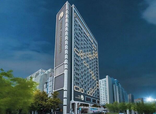 A modern hotel with a unique facade, featuring a grid of windows and a prominent vertical sign.