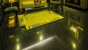 A modern living room with a green sofa, a coffee table, and a large circular light fixture. - Shaw Residenza Suites (Mandaluyong)
