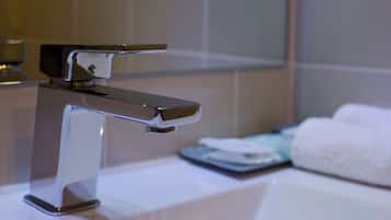 Ein modernes Badezimmer mit einem Chromarmaturen, einem weißen Waschbecken und einem Handtuch auf der Ablagefläche.