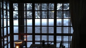 Ein Zimmer mit großen Fenstern und Blick auf eine verschneite Landschaft.