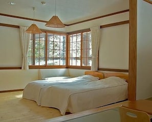 A bedroom with a large bed, two windows with curtains, and wooden paneling. - Il Bosco (Hakuba)