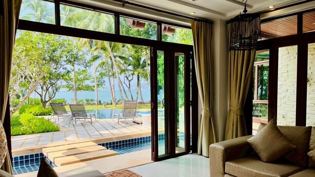 A modern living room with a large glass door leading to a pool area, a sofa, and a coffee table.