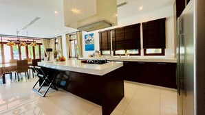 A modern kitchen with a central island, dark cabinetry, and a stainless steel refrigerator.