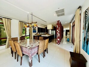 A dining area with a round table, wicker chairs, and a patterned tablecloth. - Amatapura Beach Villa 12 (Krabi)