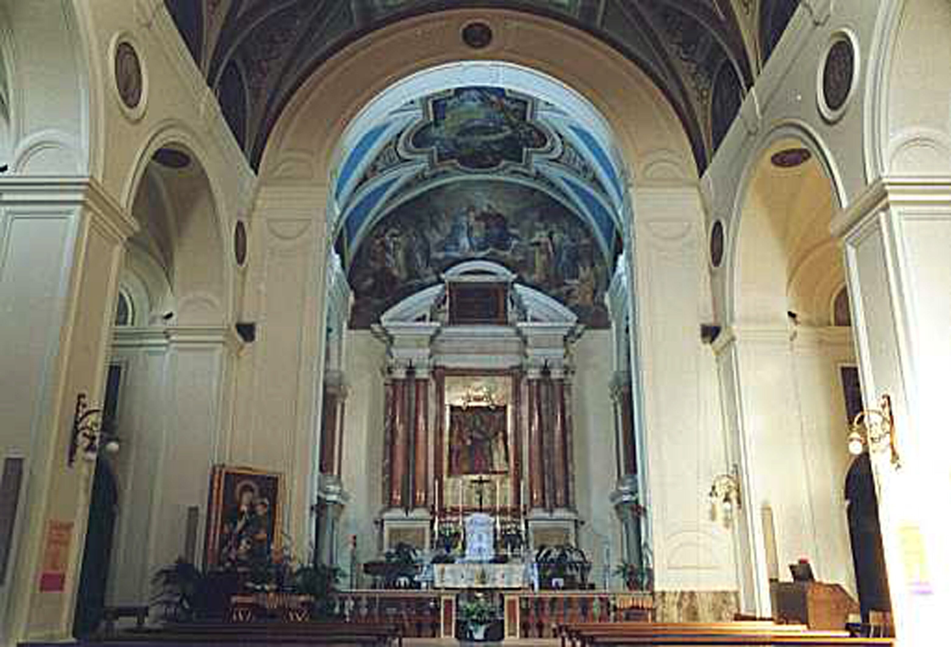 An interior of a church with an altar, pews, and a large painting above the altar.