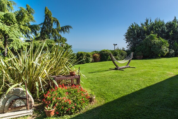 A well-maintained garden with a hammock, potted plants, and a stone structure. - Villa Capodarco B&B (Fermo)