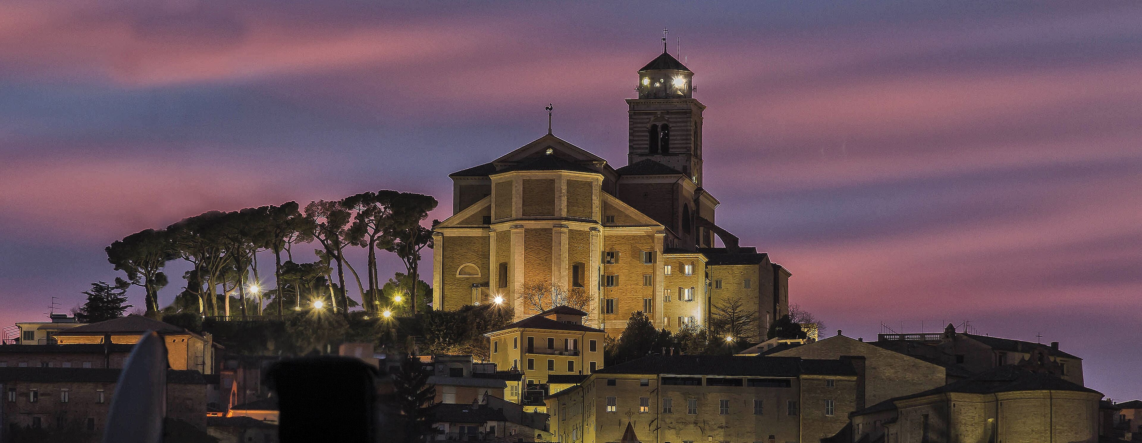Un edifici històric amb una torre destacada i una cúpula, envoltat d'arbres i altres edificis.