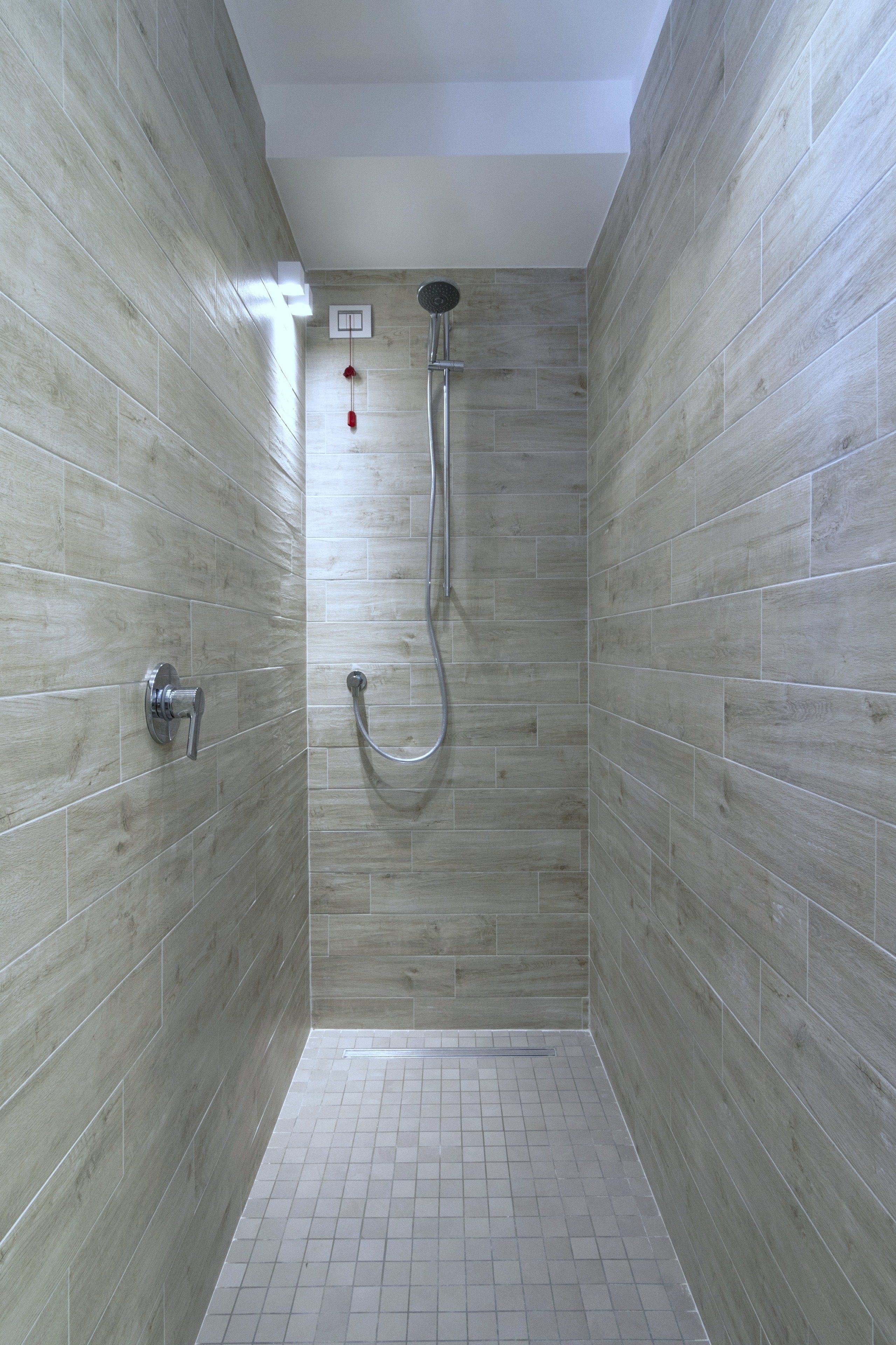 A shower with a handheld showerhead and a wall-mounted faucet.