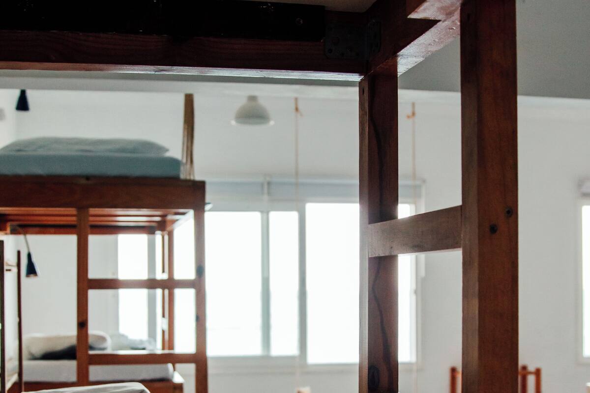 Una habitación con literas, vigas de madera y vistas a otra habitación por un umbral abierto.