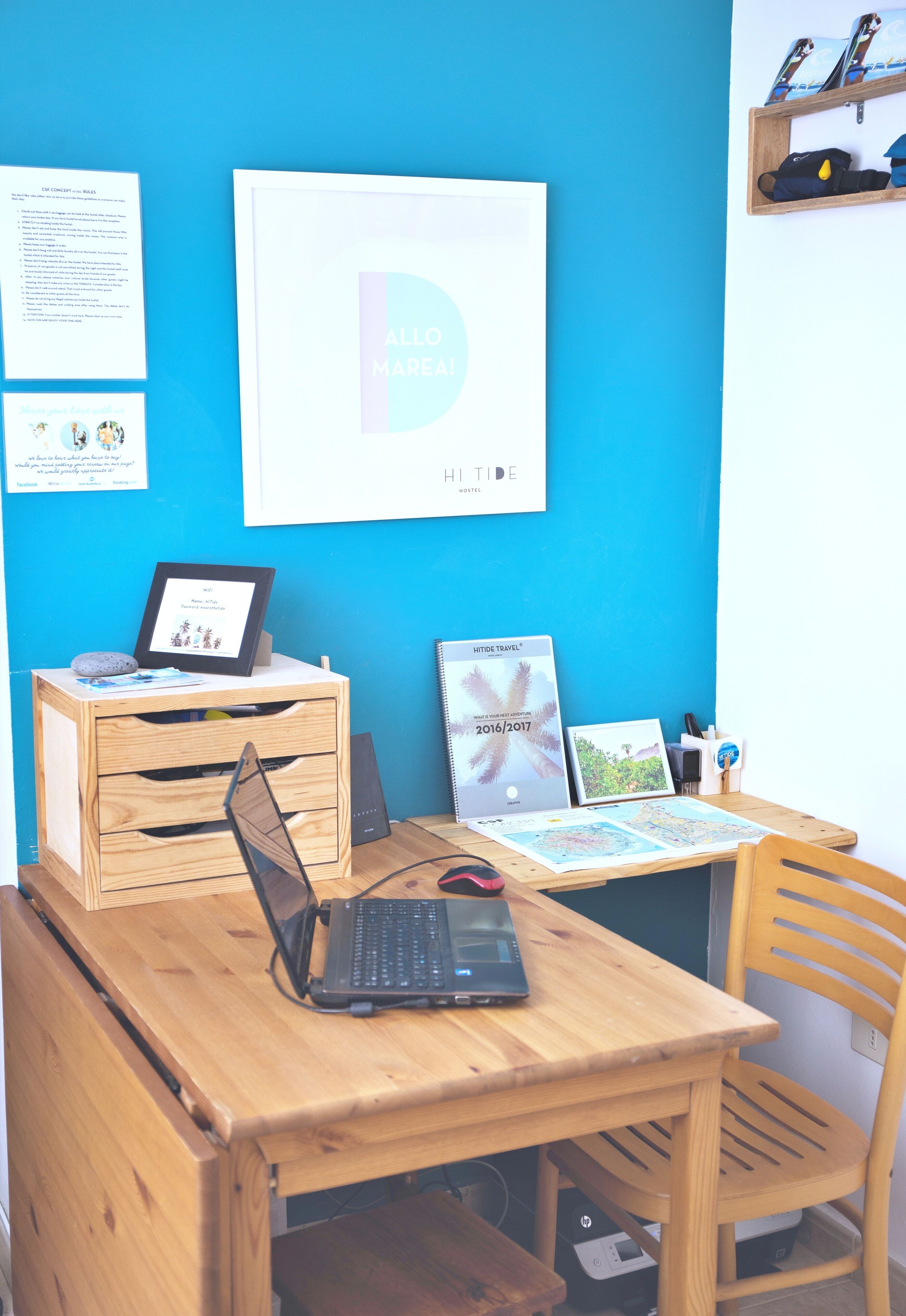 A wooden desk with a laptop, a framed certificate, and a travel brochure.