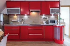 Cozinha moderna com armários vermelhos, eletrodomésticos de aço inoxidável e um micro-ondas.