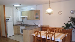 A compact kitchen with a dining area, wooden cabinets, a microwave, and a sink.