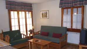 A living room with a sofa, two armchairs, a coffee table, and a radiator.