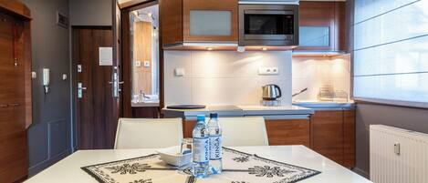 A modern kitchen with wooden cabinets, a microwave, and a dining table with chairs.