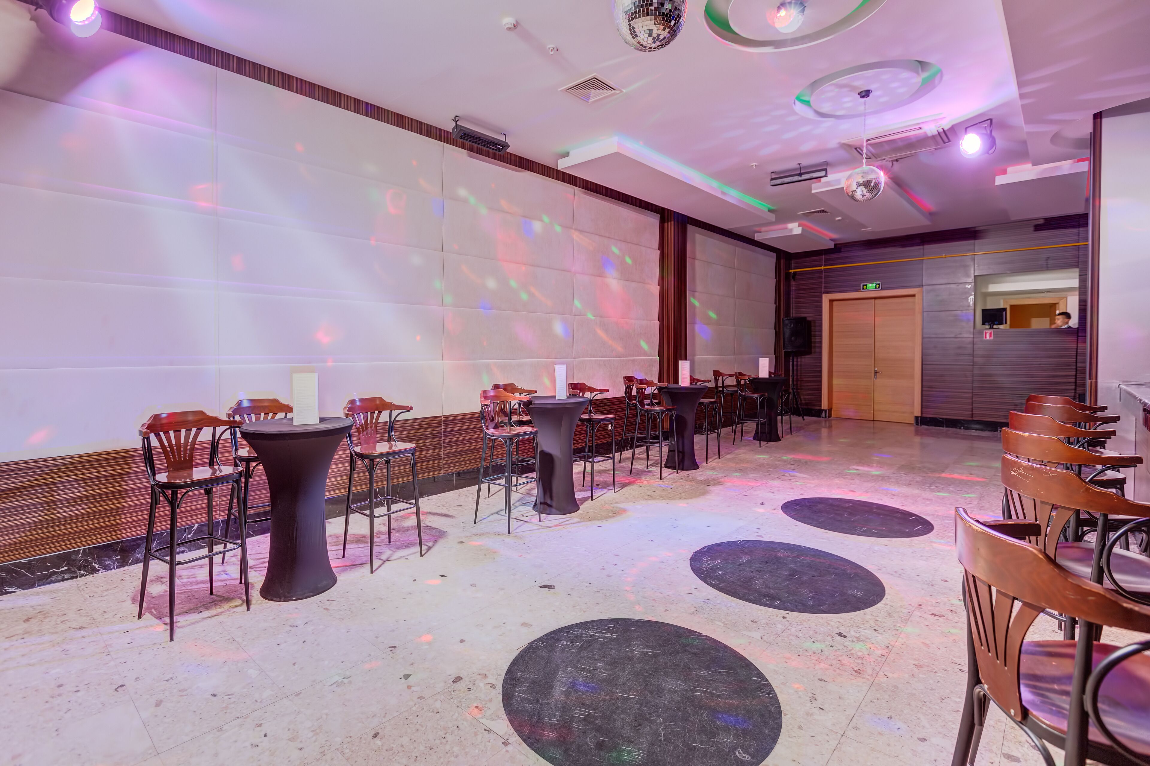 A spacious hall with a stage, multiple tables, and chairs arranged for an event.